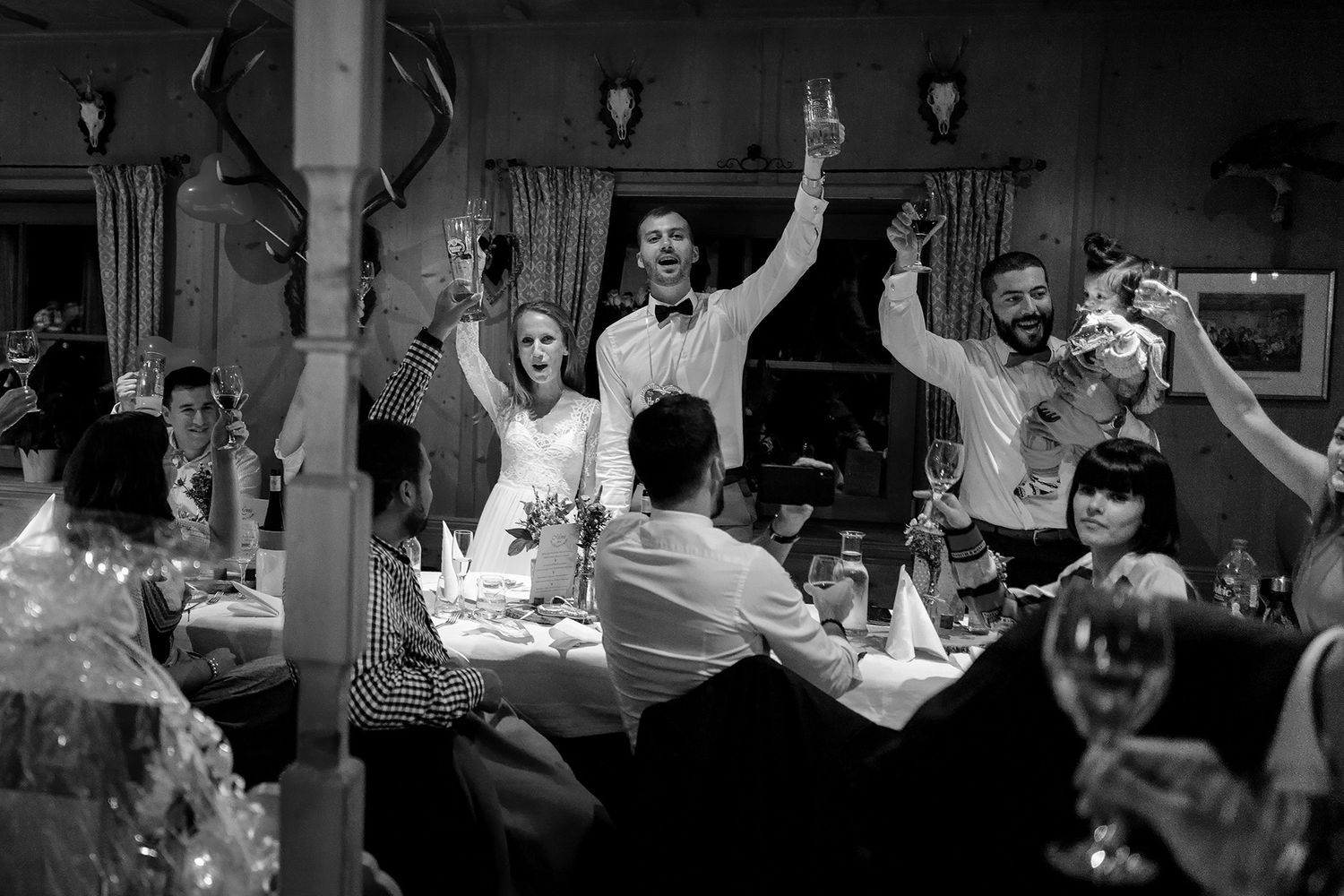 Fröhliche Hochzeitsgesellschaft stößt am Tisch an: Echte Reportage-Fotografie im Niederrhein, voller Freude und ungestellt.