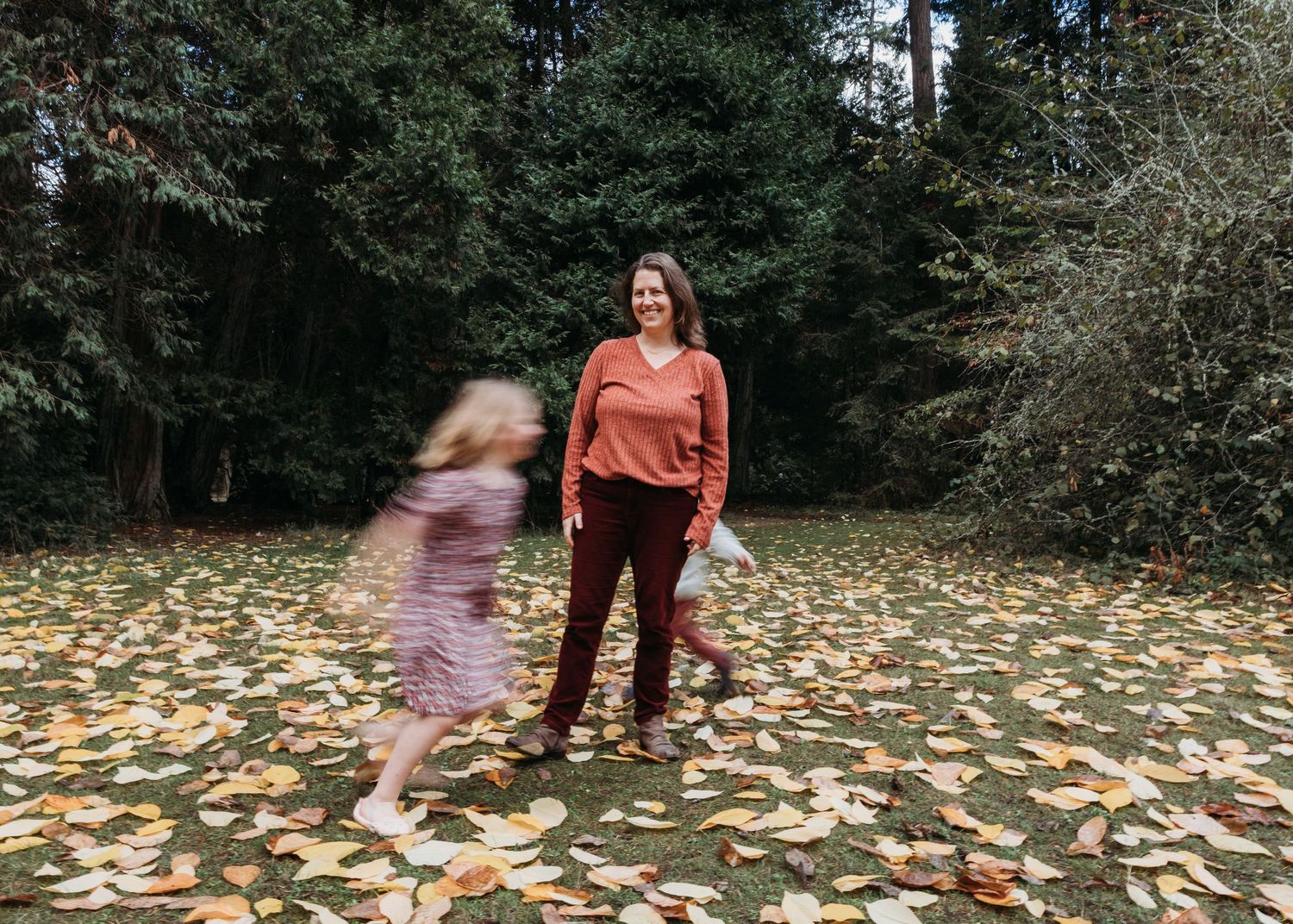 A sequence of autumn photos shows someone playing in fallen leaves on a forest path.