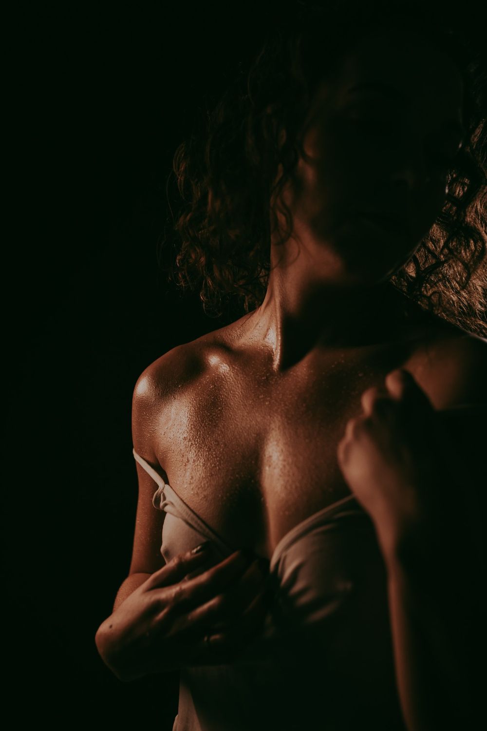 Artistieke foto van een vrouw met een shirt in het wit met druppels over haar lijf