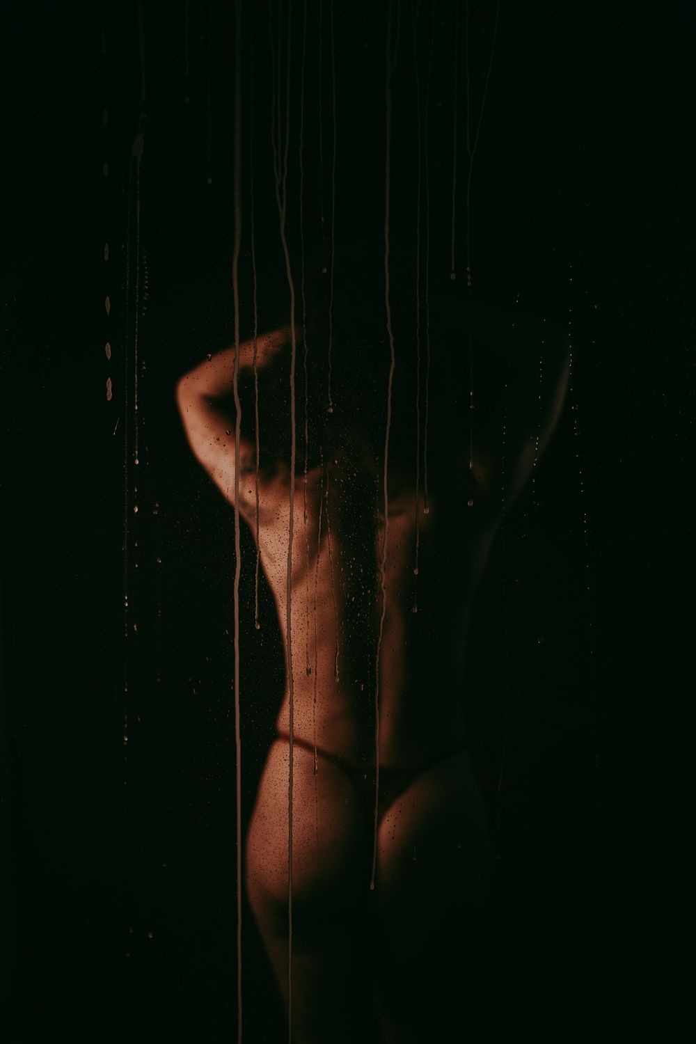 Artistieke foto in boudoistijl van een vrouw met rondingen en een donkere achtergrond