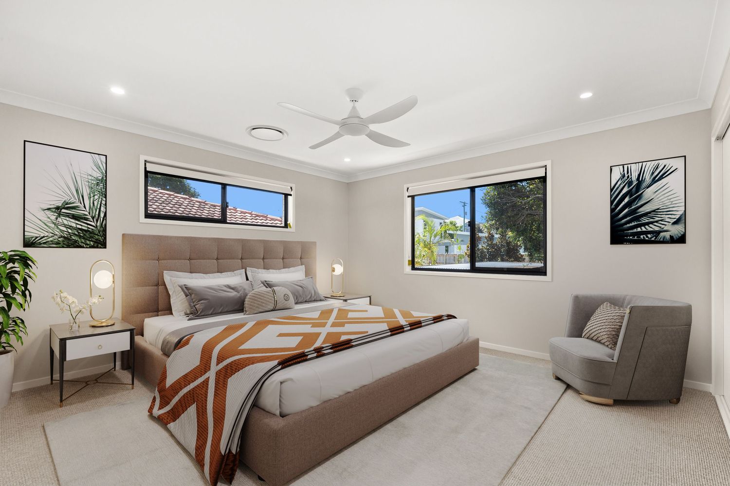 Modern master bedroom with upholstered bedhead, ceiling fan, dual windows, and neutral carpet flooring.