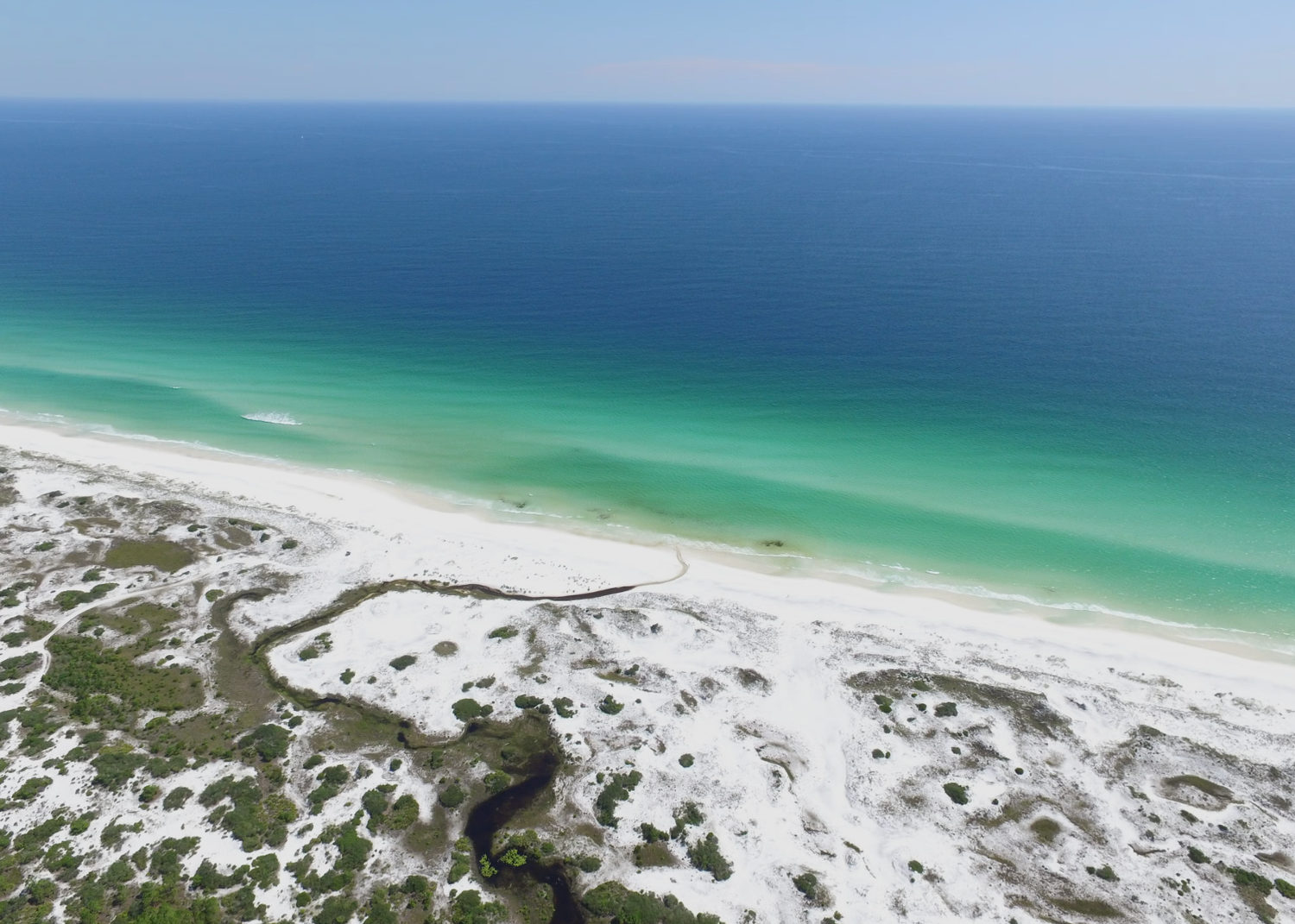 Aerial view of pristine white sand beaches and turquoise waters along the Gulf Coast shoreline.