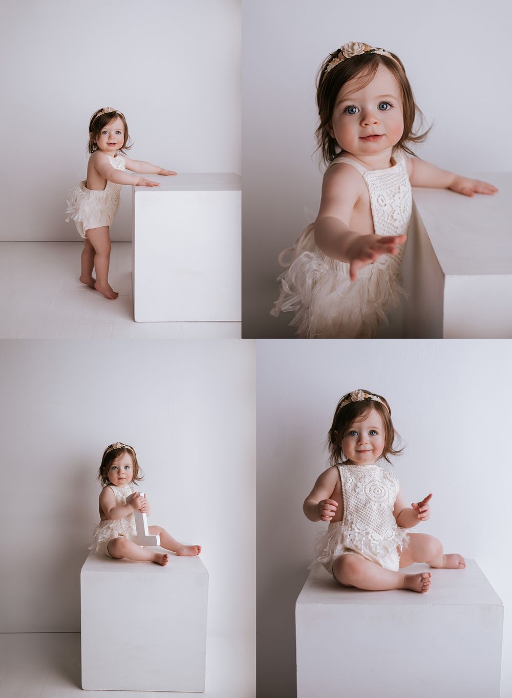 A baby in a white lace dress poses gracefully against a minimalist white backdrop during a professional photo session.