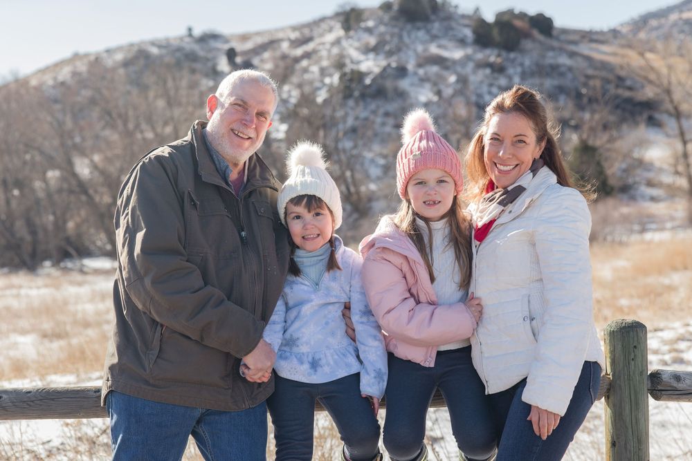 Family enjoying a winter photoshoot together in a snowy mountain landscape with natural lighting.