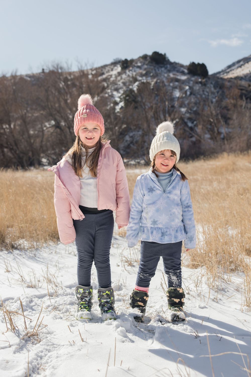Two people playing in the snow on a winter mountainside wearing warm coats and winter hats.