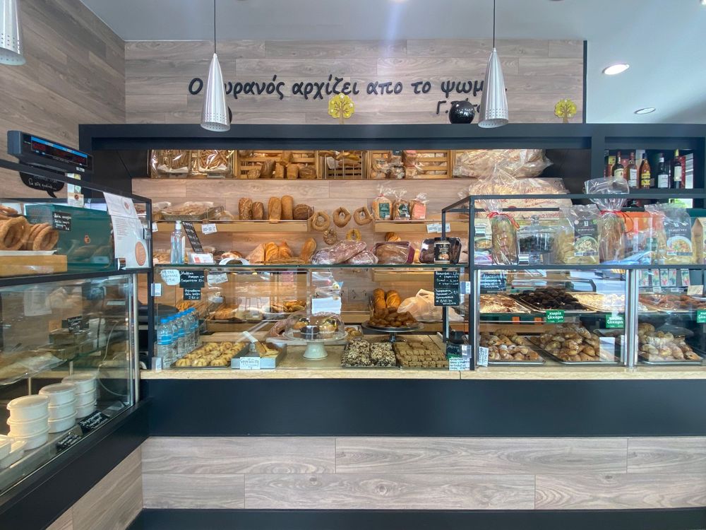 Interior view of a modern bakery display case showing various breads, pastries and baked goods for sale.