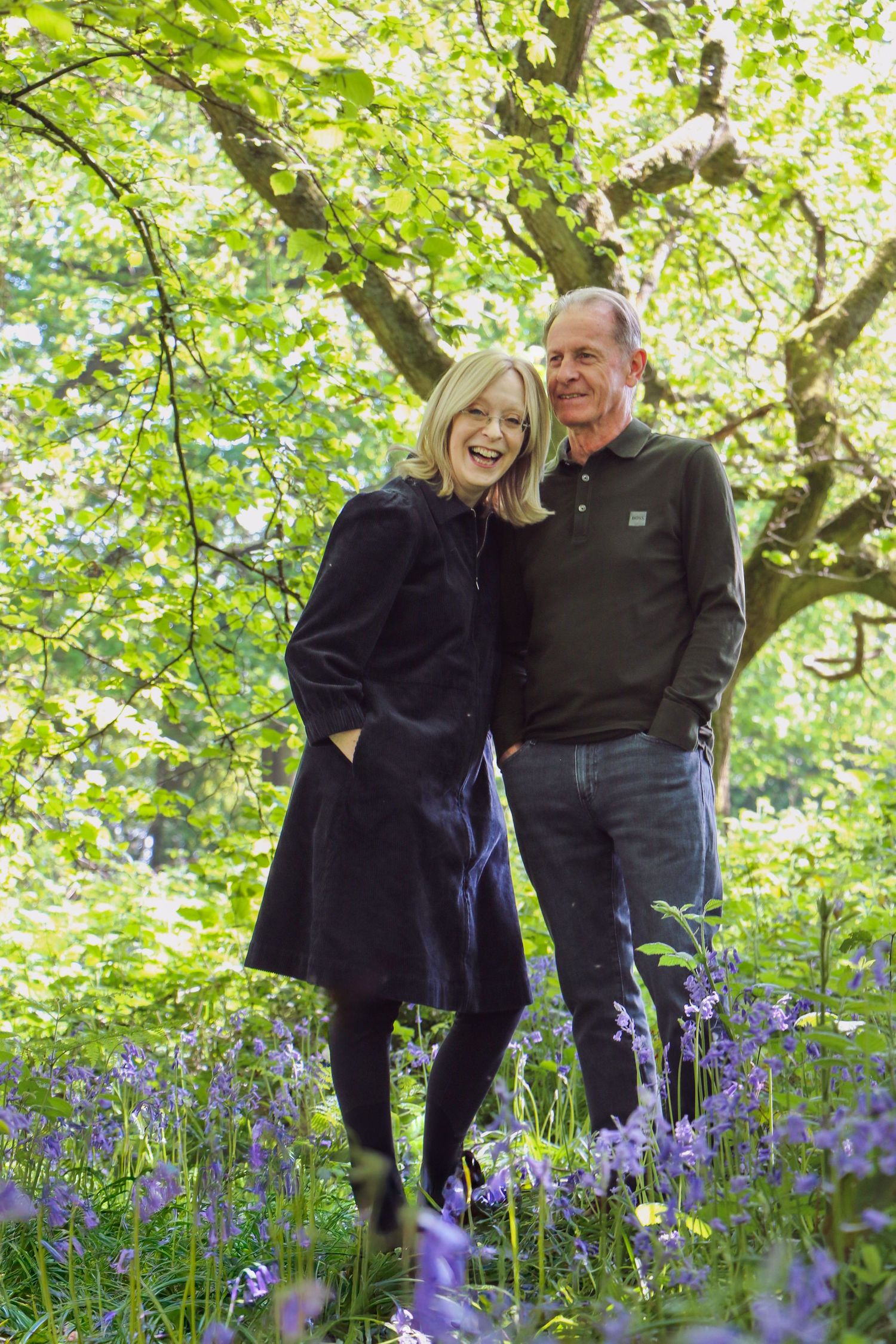 A couple shares a joyful moment together in a spring garden surrounded by blooming purple bluebells and green foliage.