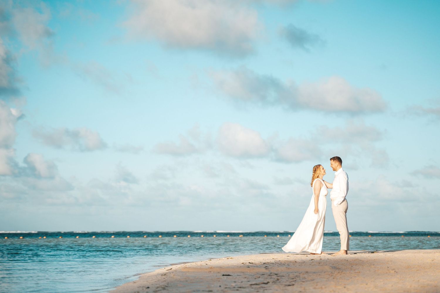 Scenic beach landscape with turquoise waters and couple in distance.