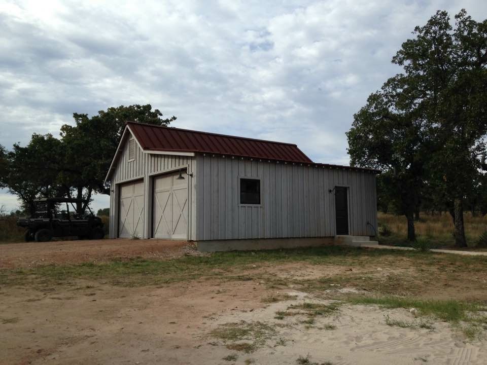 Rural property with multiple farm buildings and metal roofs on open land.