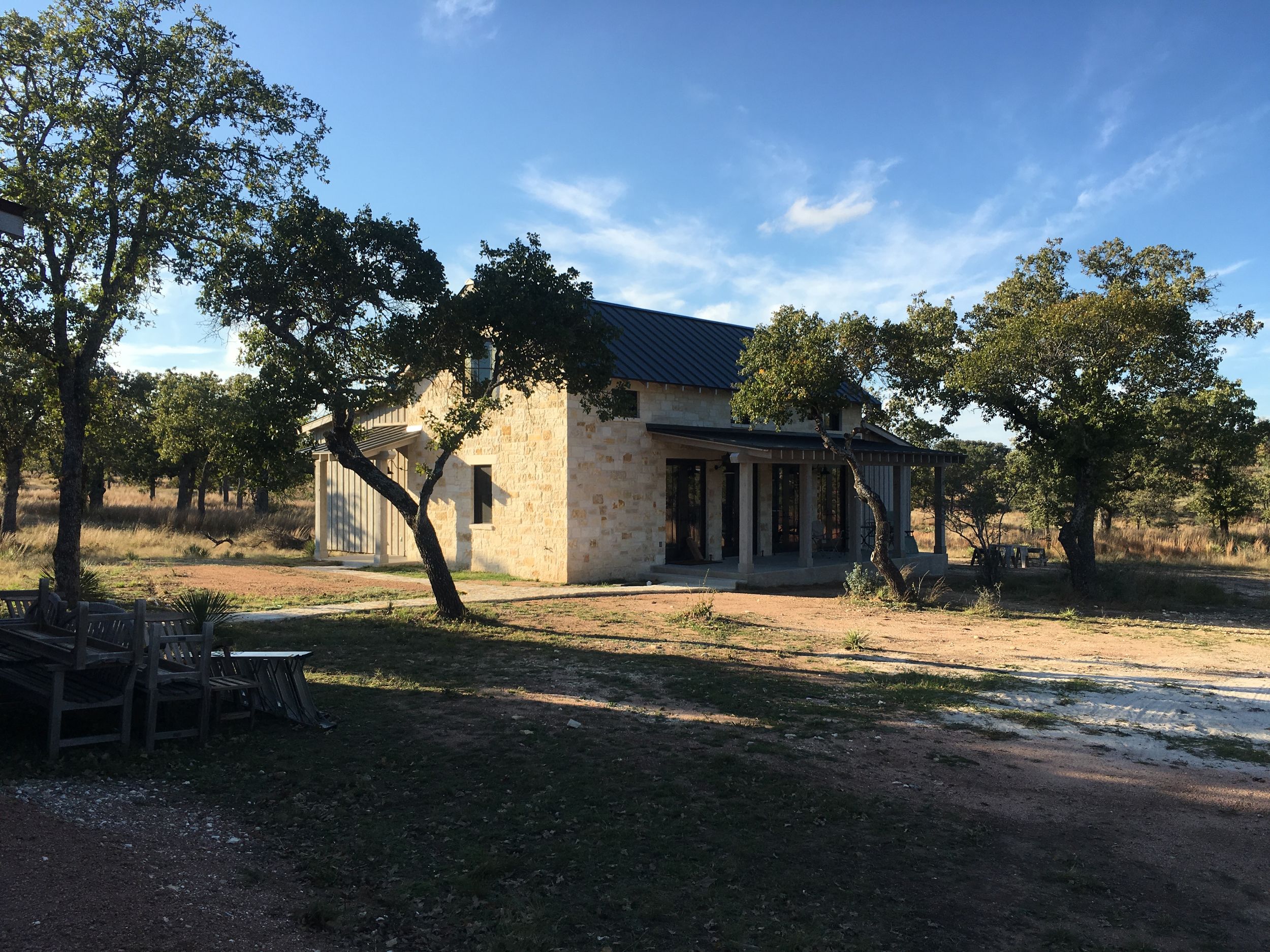 Wide angle view of a modern ranch house under construction with oak trees in the background.