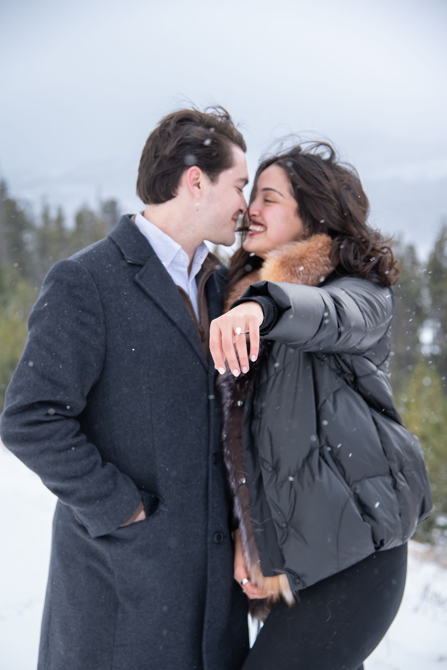 Romantic couple with woman showing off her new engagement ring after a surprise winter proposal photo at Sapphire Point