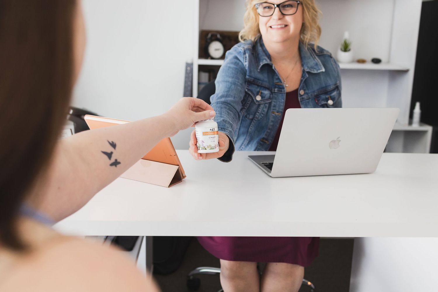 Maple Valley Acupuncture, WA branding photo of female receptionist handing over recommended herbal supplement to female client sitting