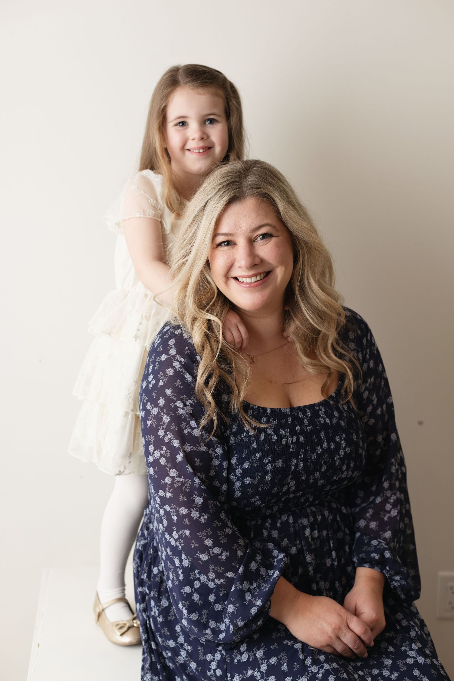 A series of portraits showing someone in a navy floral dress against a light beige background.