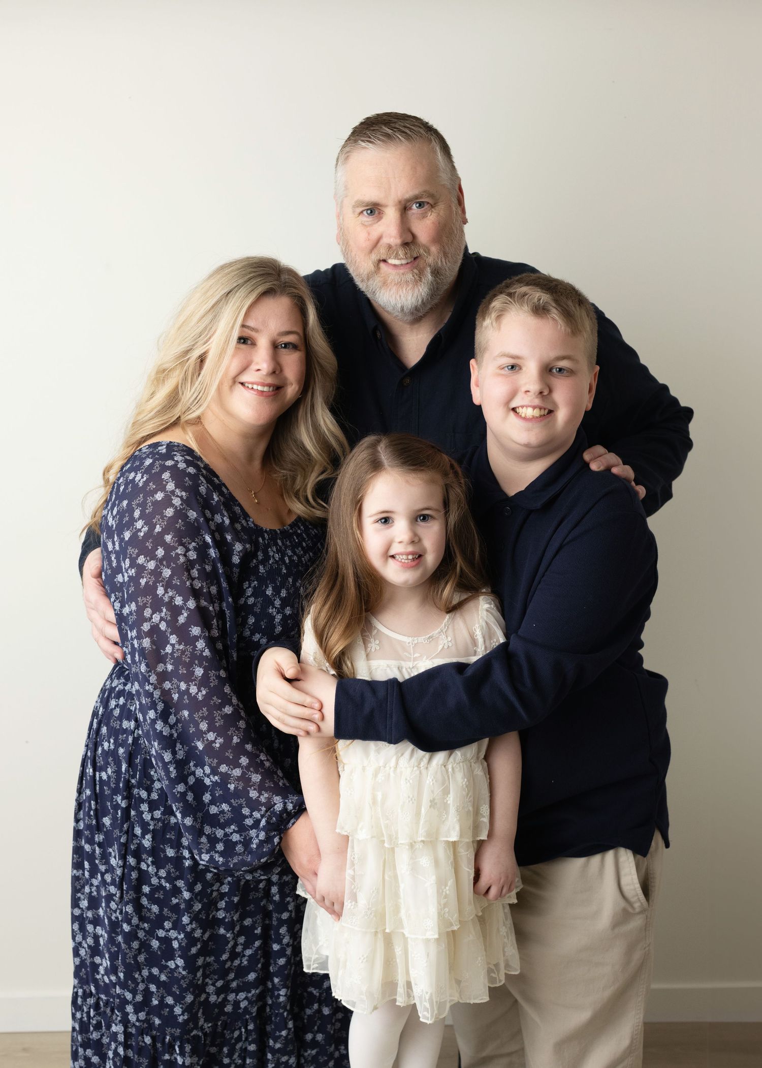Family portrait session showing a group in coordinated outfits against a light background in multiple poses.