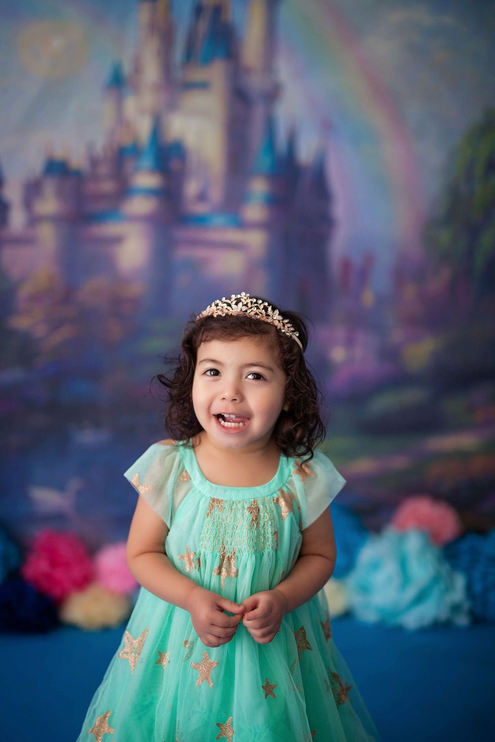 A child in a mint green dress poses against a dreamy blue and purple backdrop for a portrait session.