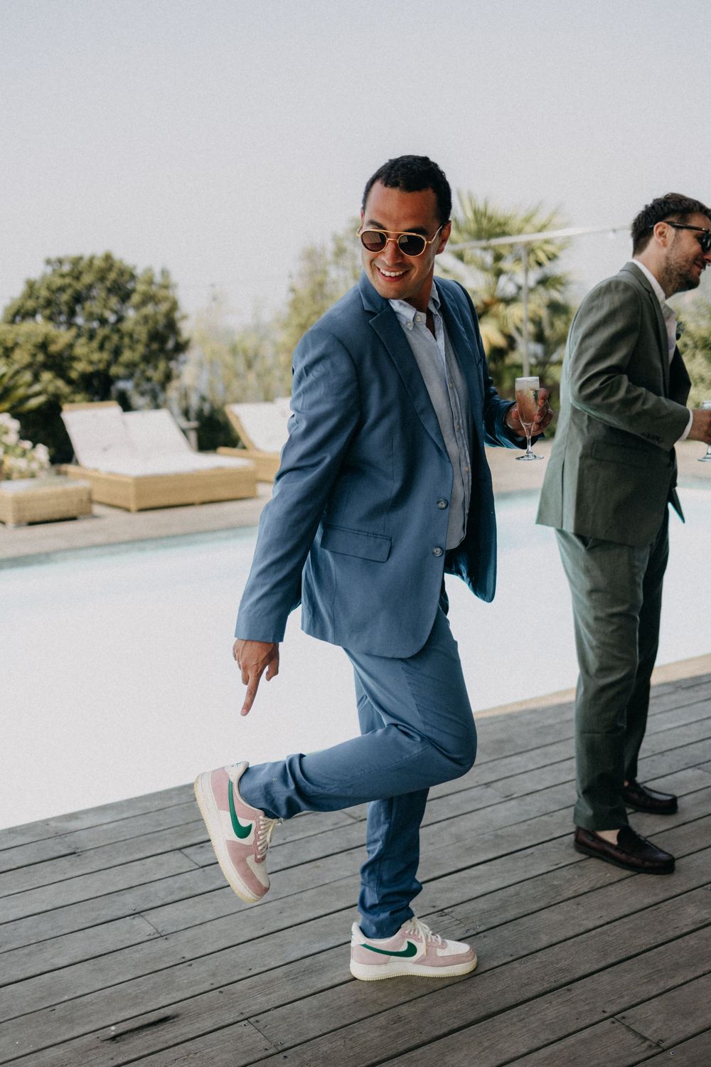 Person in blue suit shows off stylish sneakers while posing on wooden deck.