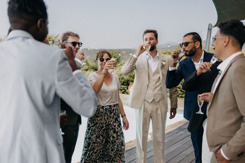 A group of friends celebrating outdoors on a deck, laughing and raising drinks together in a festive moment.