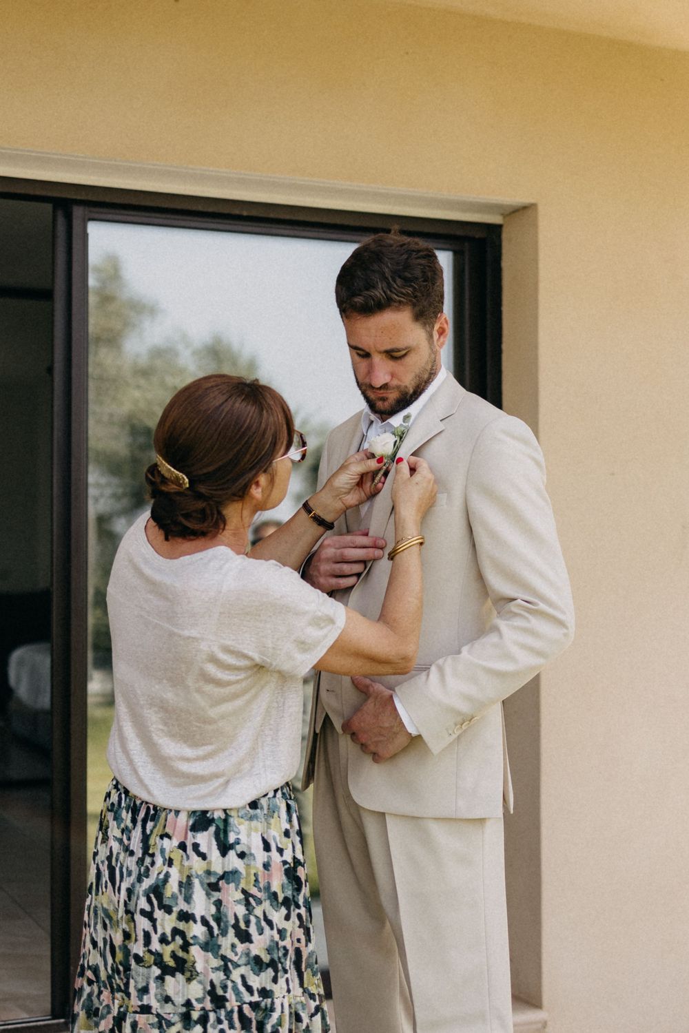 Wedding preparations showing formal attire adjustments on a covered porch.