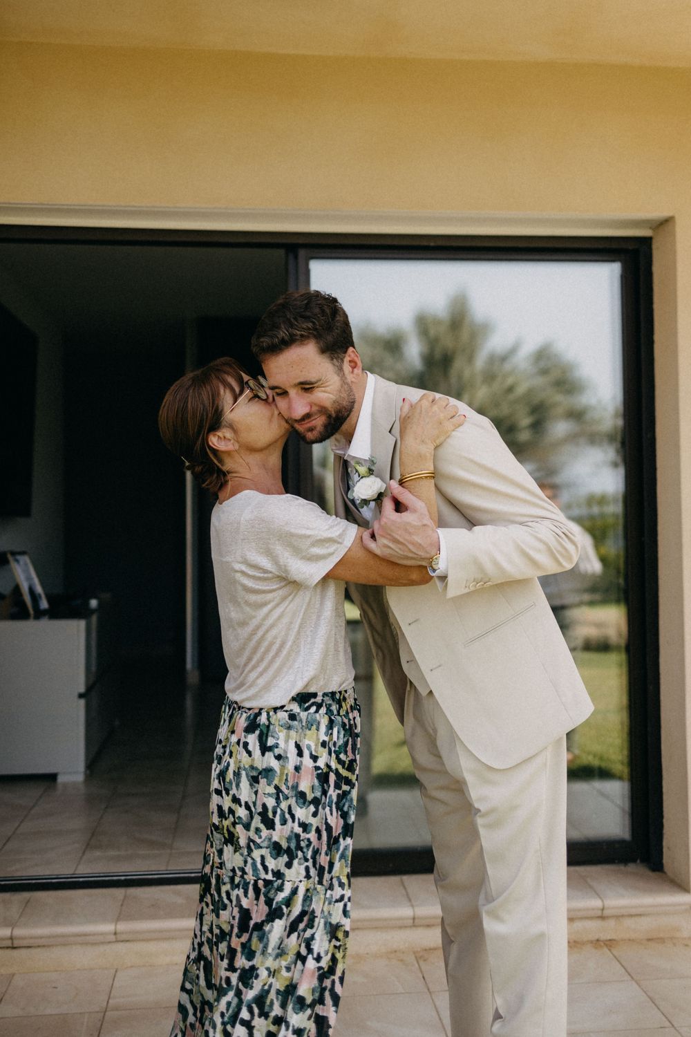 Romantic couple in white and floral attire dancing together in a sunlit room.