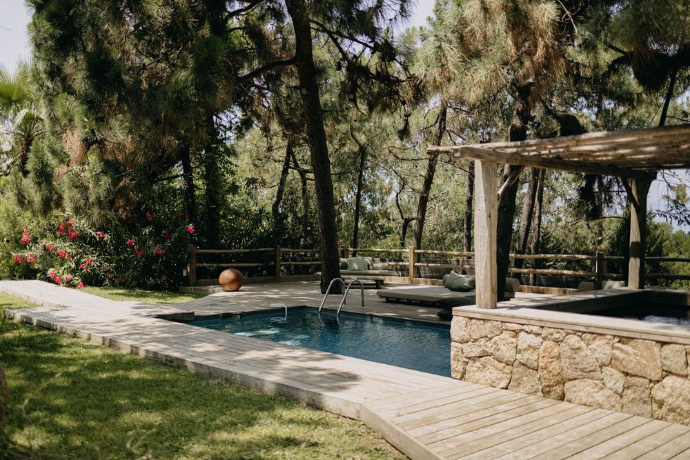 A serene outdoor venue with stone walls and a swimming pool surrounded by trees and natural landscaping.