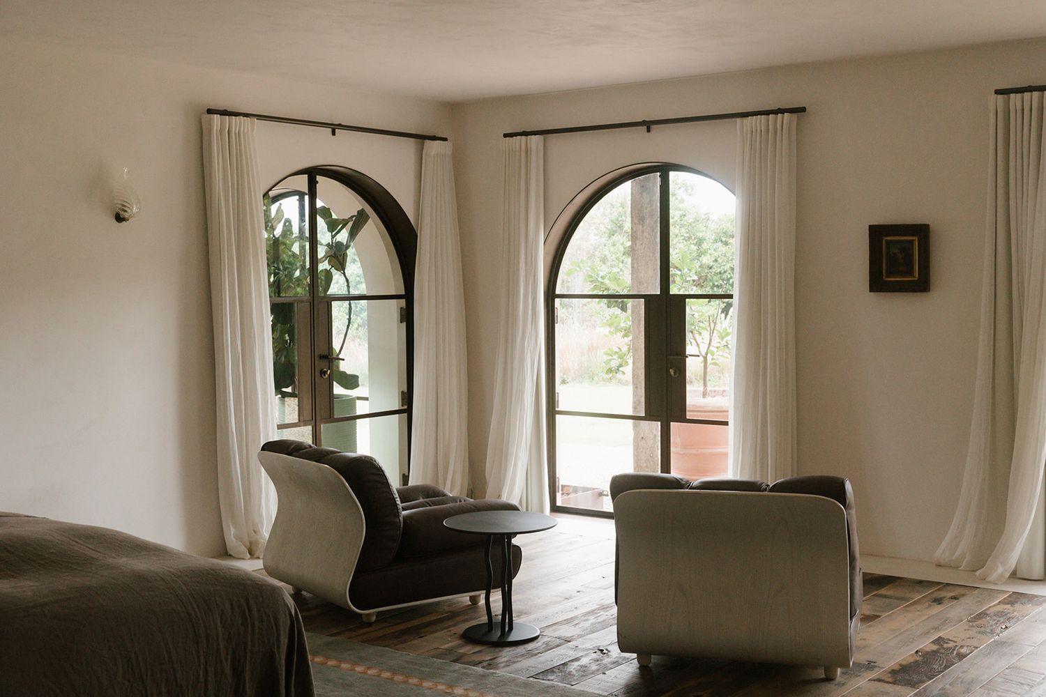 Empty room with white curtains, large windows, and hardwood flooring in a bright, minimalist interior space.