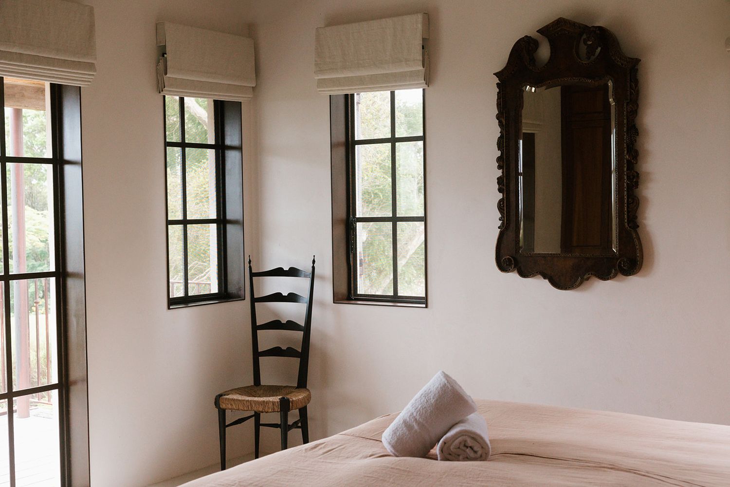 Panoramic view of a bright white room with multiple windows and antique wooden chairs along the walls.