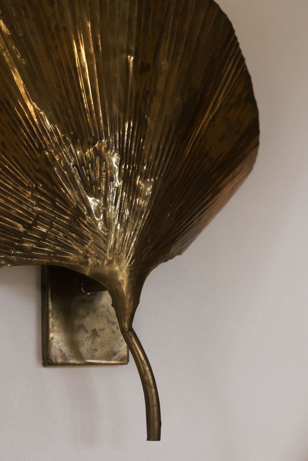 Multiple views of a vintage brass fan-shaped wall sconce or decorative element with textured ridges against a white background.