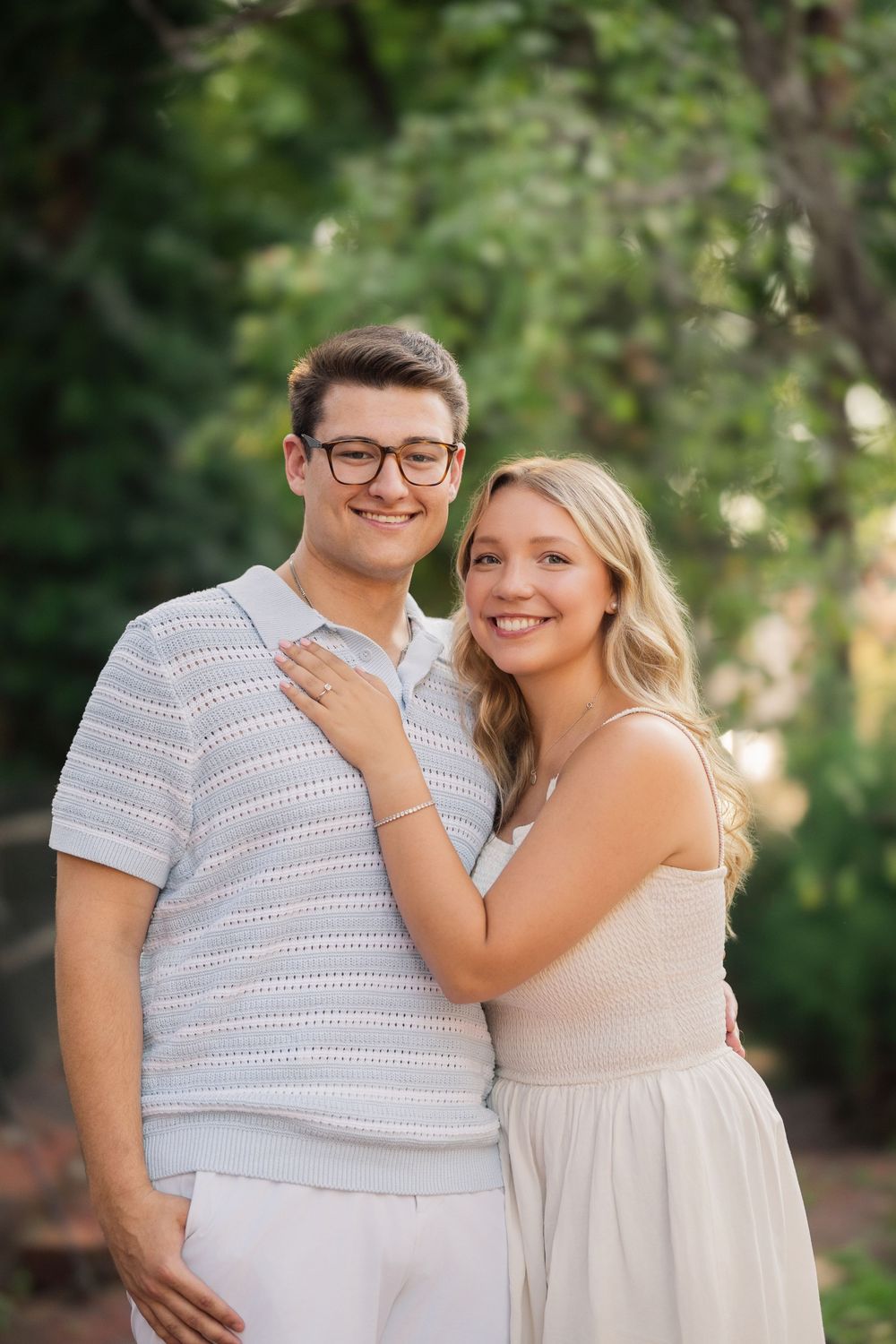 A couple in coordinating light-colored outfits smiling together during an outdoor portrait session in a garden setting. German Village