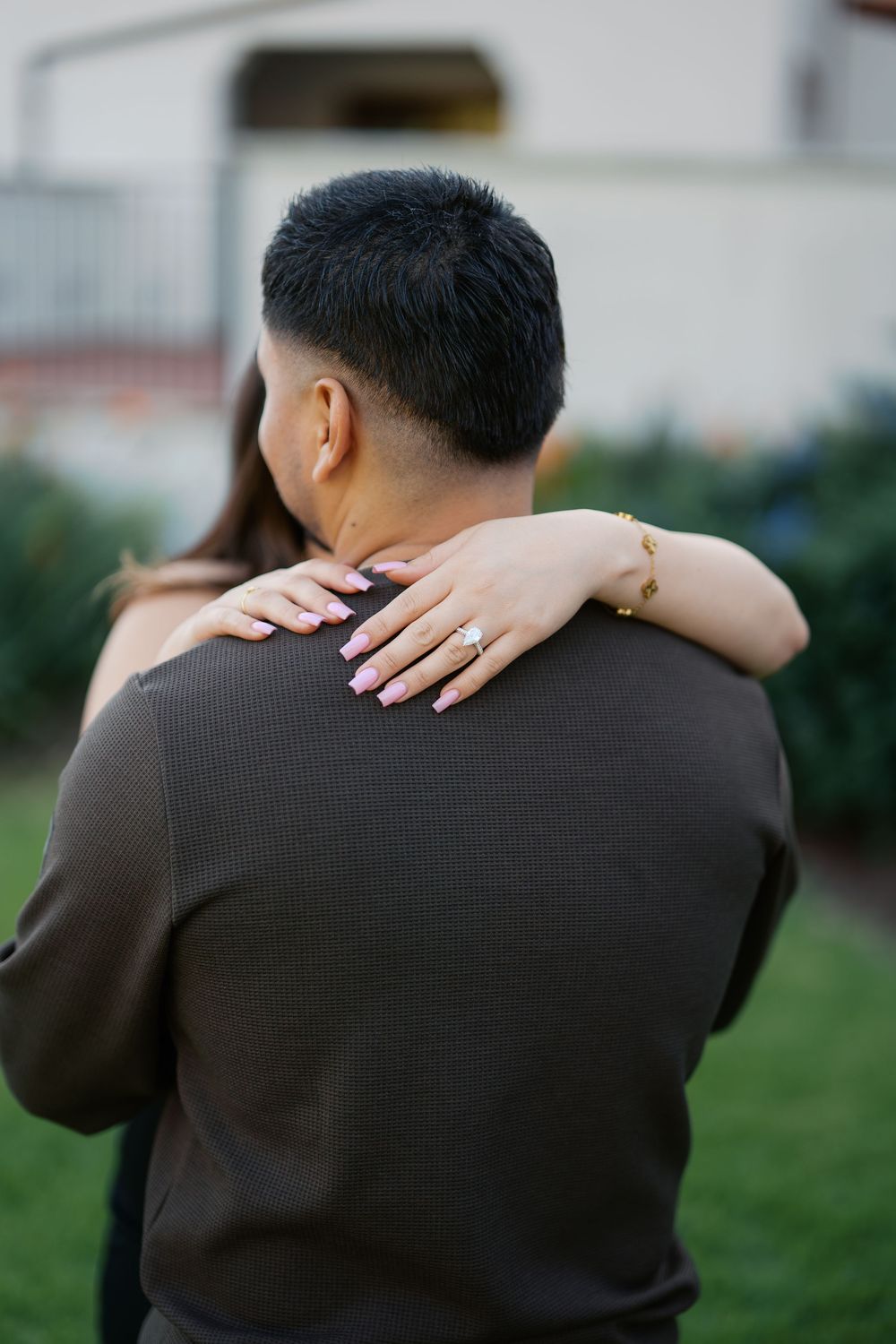 A couple embraces in an outdoor setting, shown in a series of intimate cropped photos wearing dark clothing.