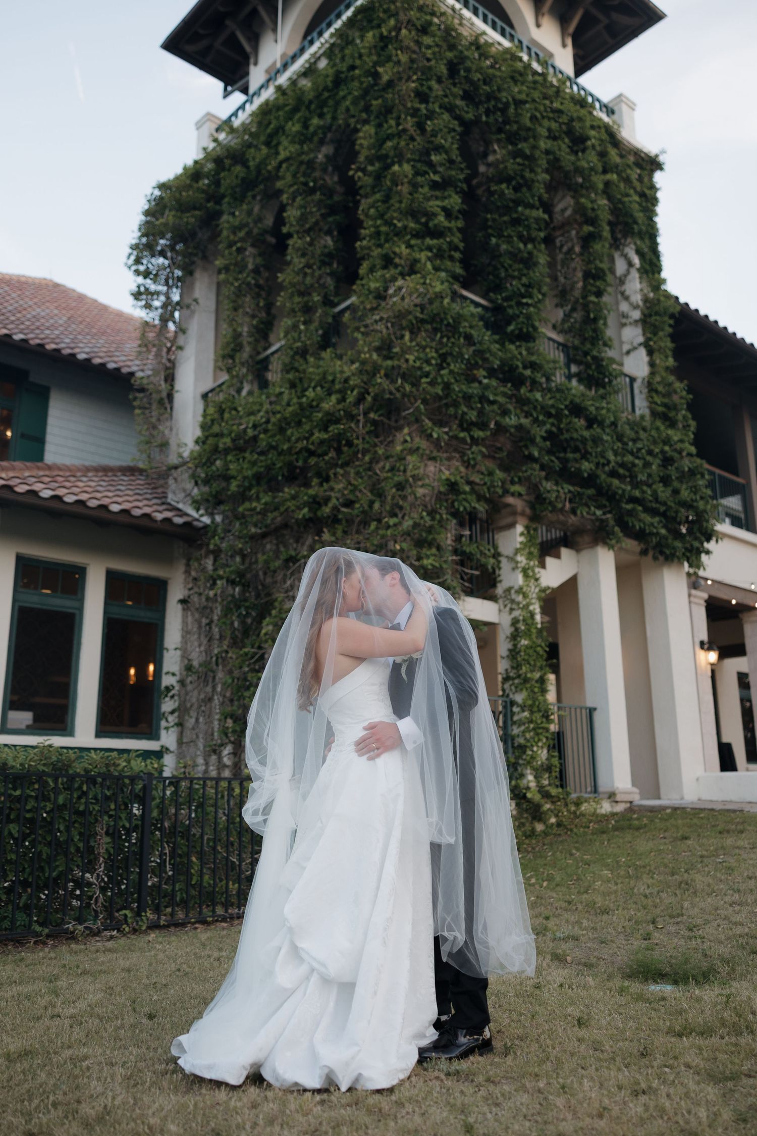 Wedding party in sage green attire posing playfully under large oak trees.