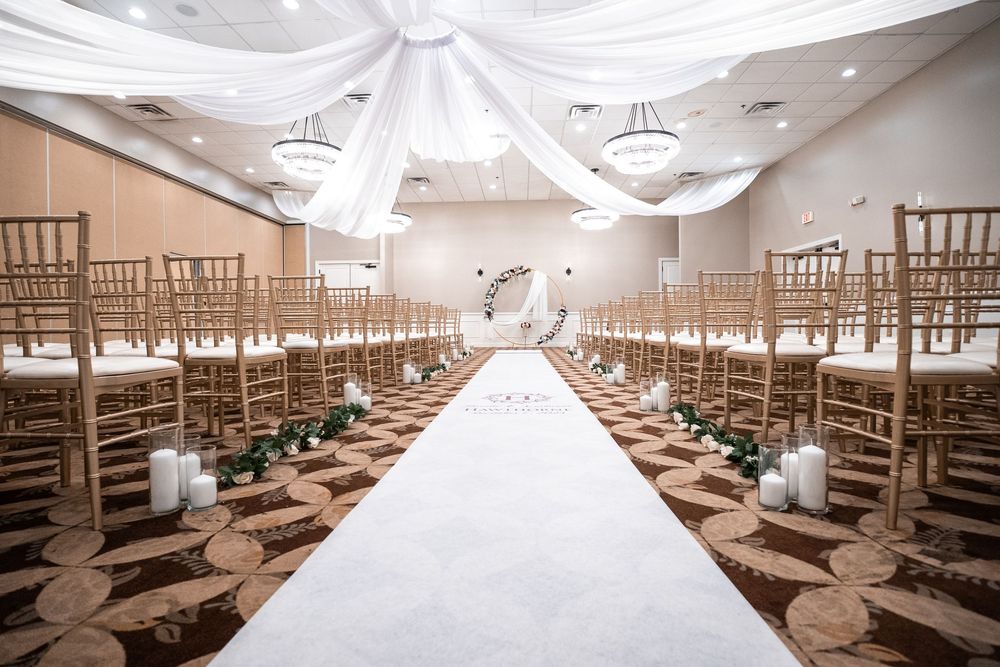 Elegant wedding ceremony space with white fabric draped from ceiling and wooden chiavari chairs lined in rows at Carollwood Country Club