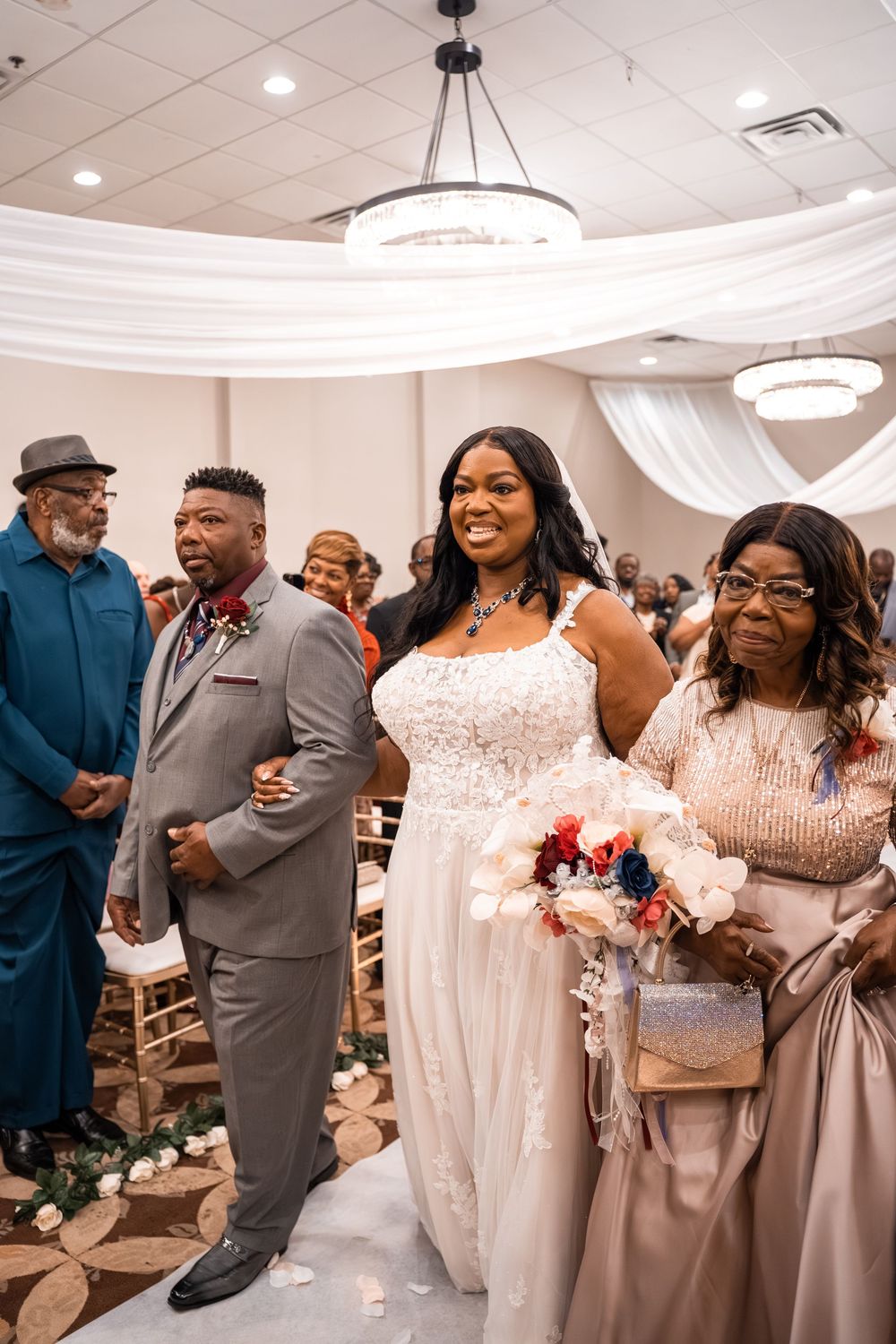 Wedding guests dance and celebrate together in an elegant white reception hall with round chandeliers at Carollwood Country Club in Tampa