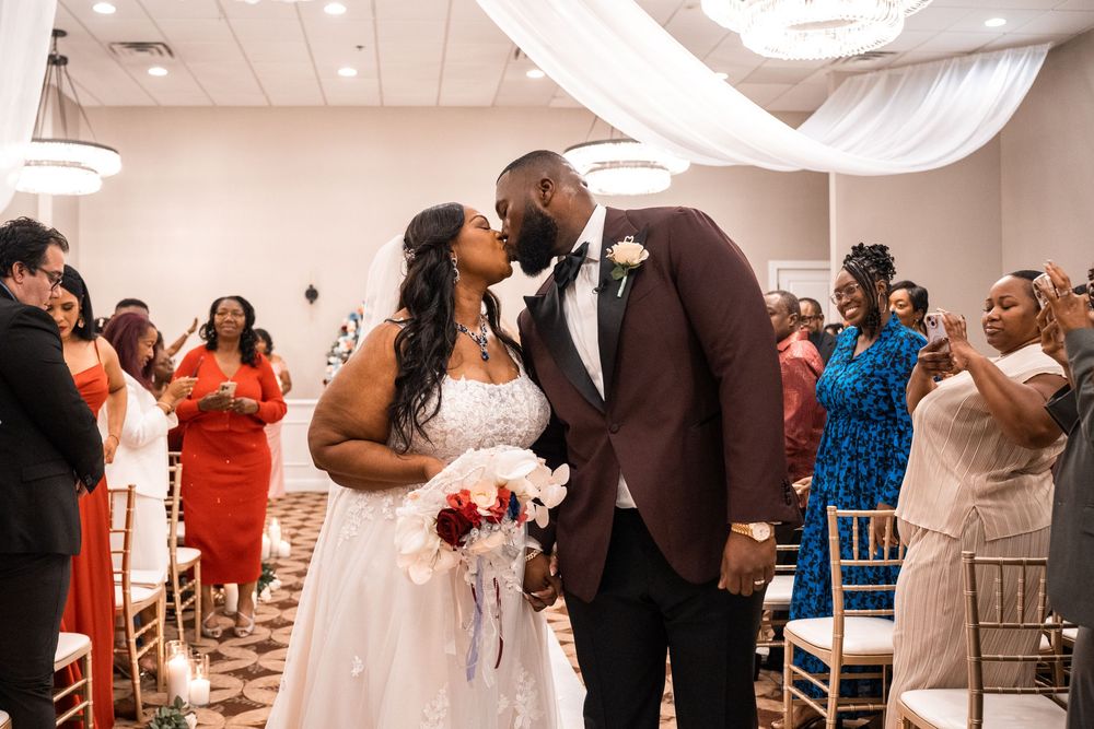 Newlyweds share their first kiss during wedding ceremony while guests capture the moment at Carollwood Country Club in Tampa, Florida