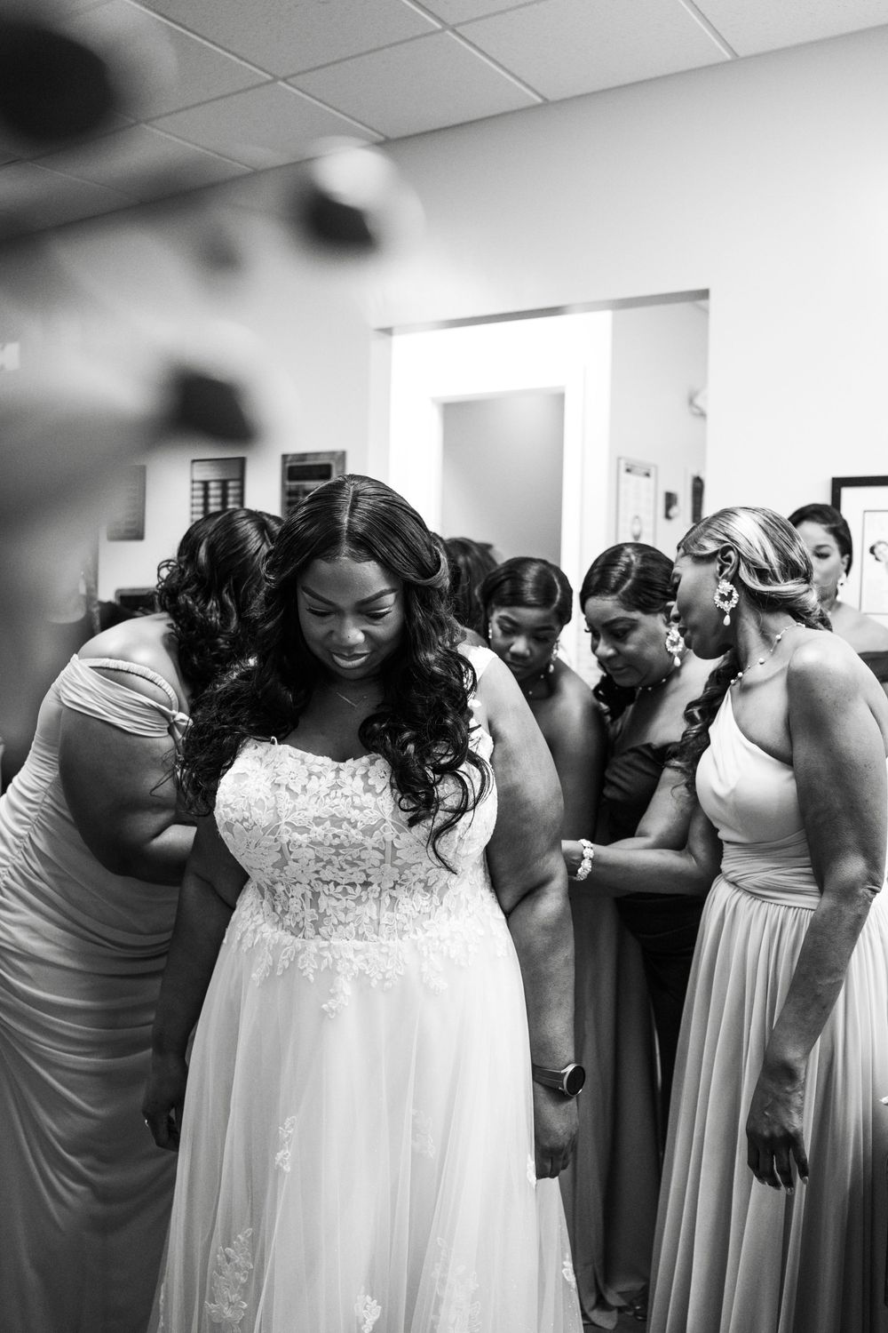 Wedding party members in matching gray dresses and white gowns lean together in a playful group pose at Carollwood Country Club in Tampa, Fl