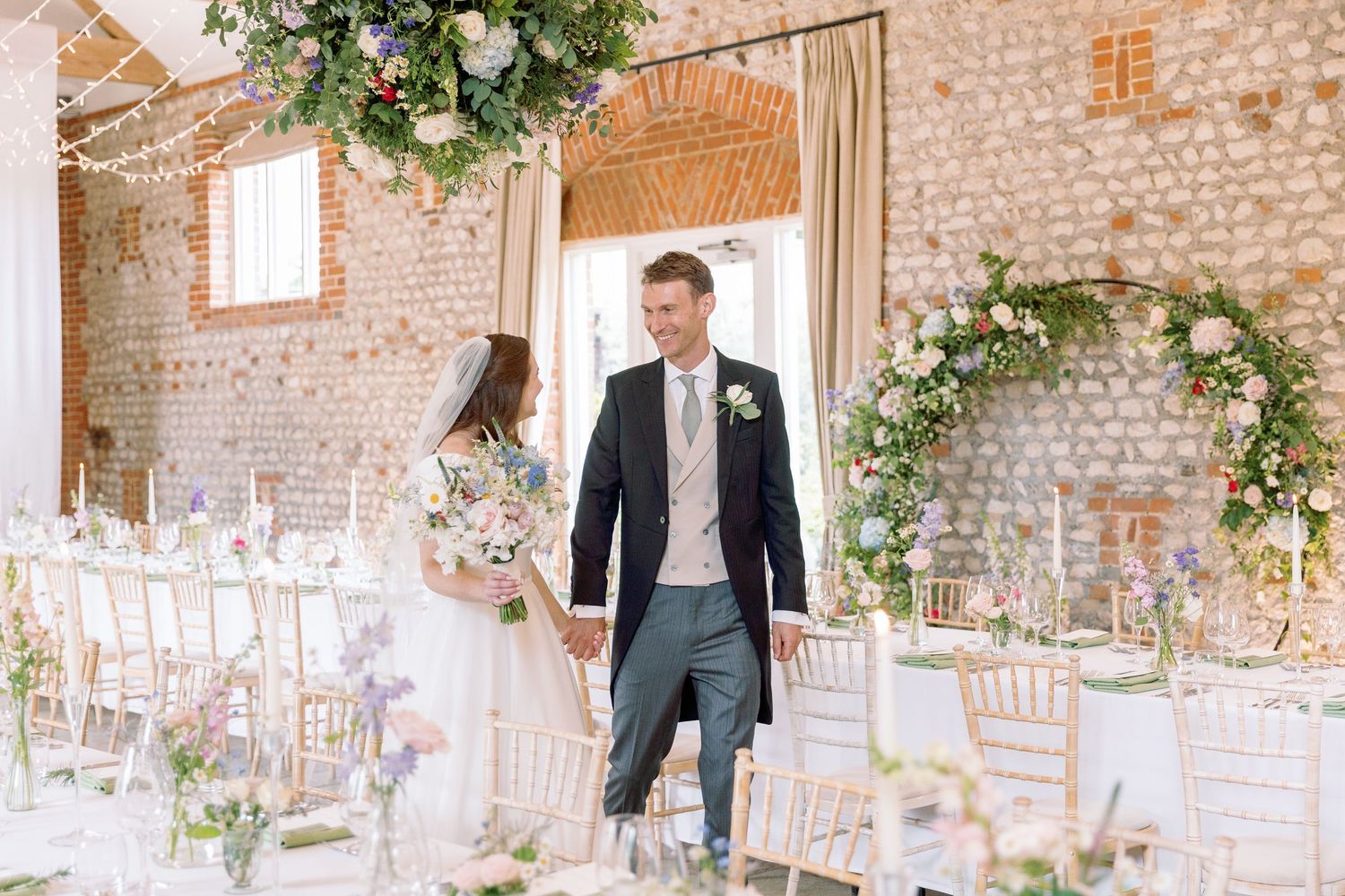 Elegant rustic barn wedding venue, Farbridge, with exposed brick walls and white floral decorations adorning the space.