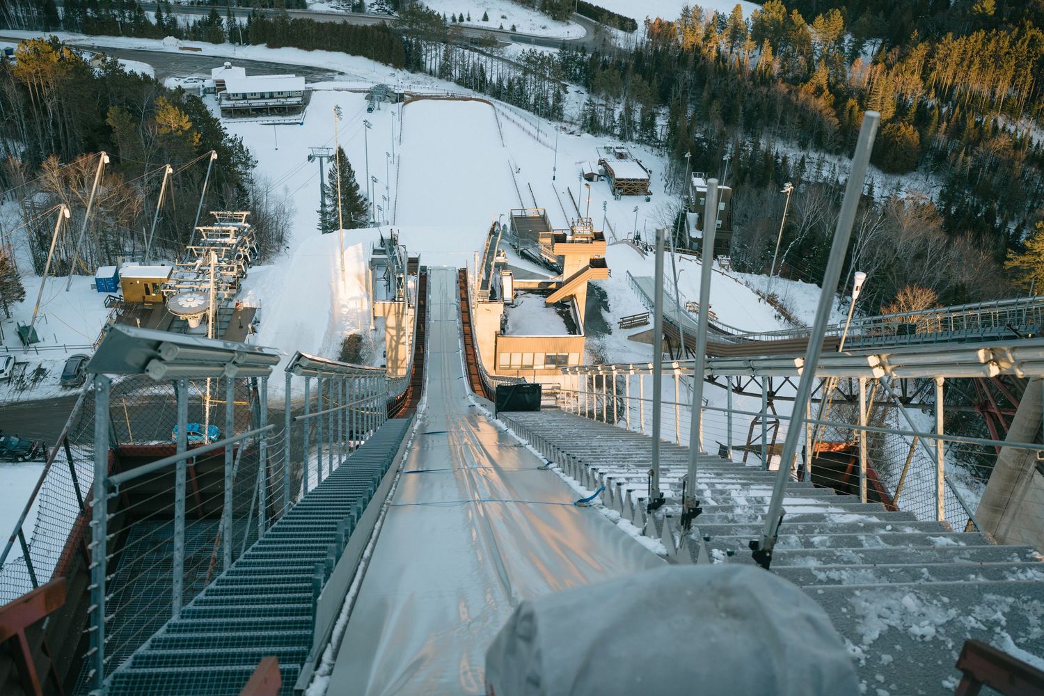 Looking down from the top of a snowy ski slope with chairlifts and winter resort buildings visible below.