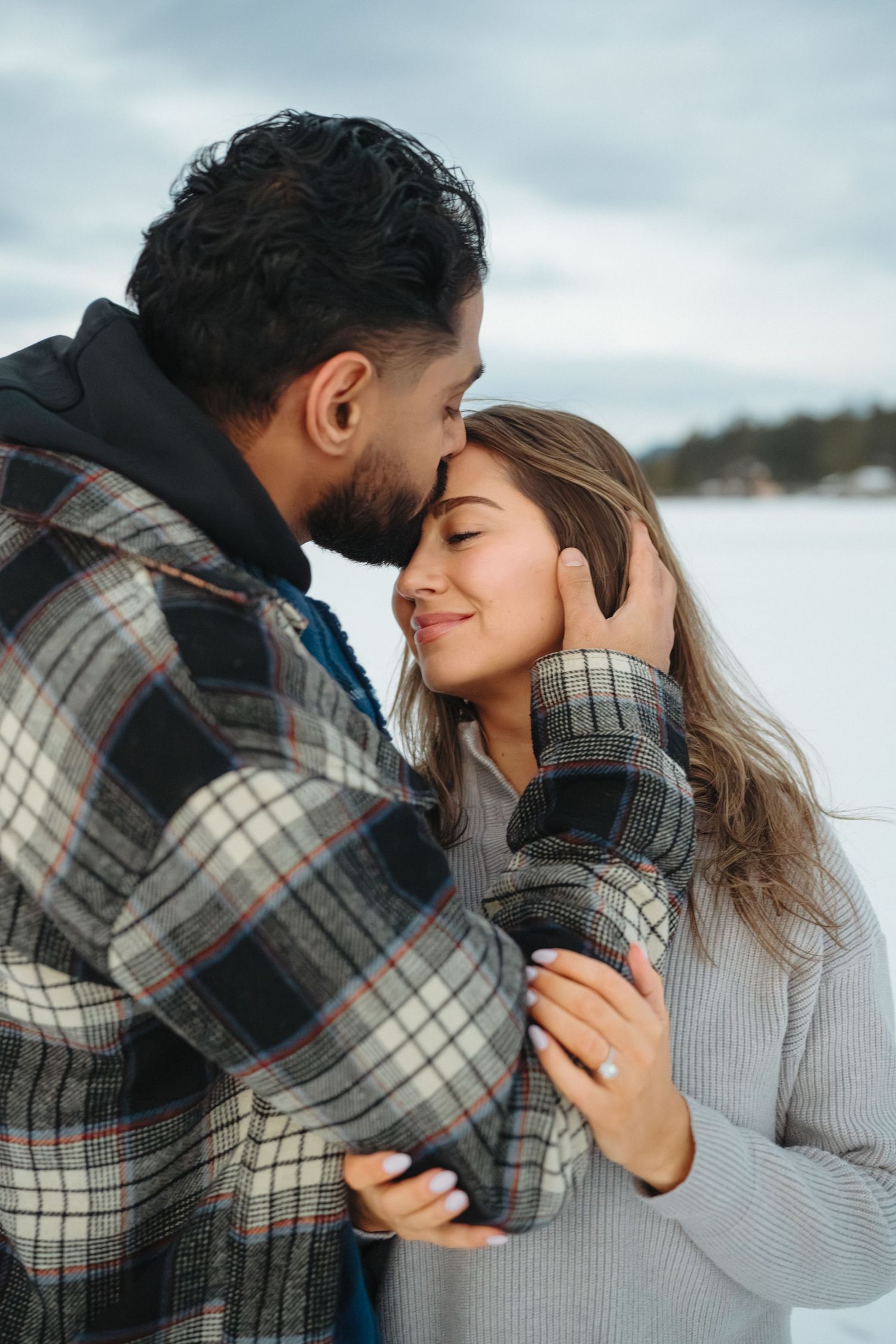 Romantic couple embracing in a series of tender moments against a winter landscape backdrop.