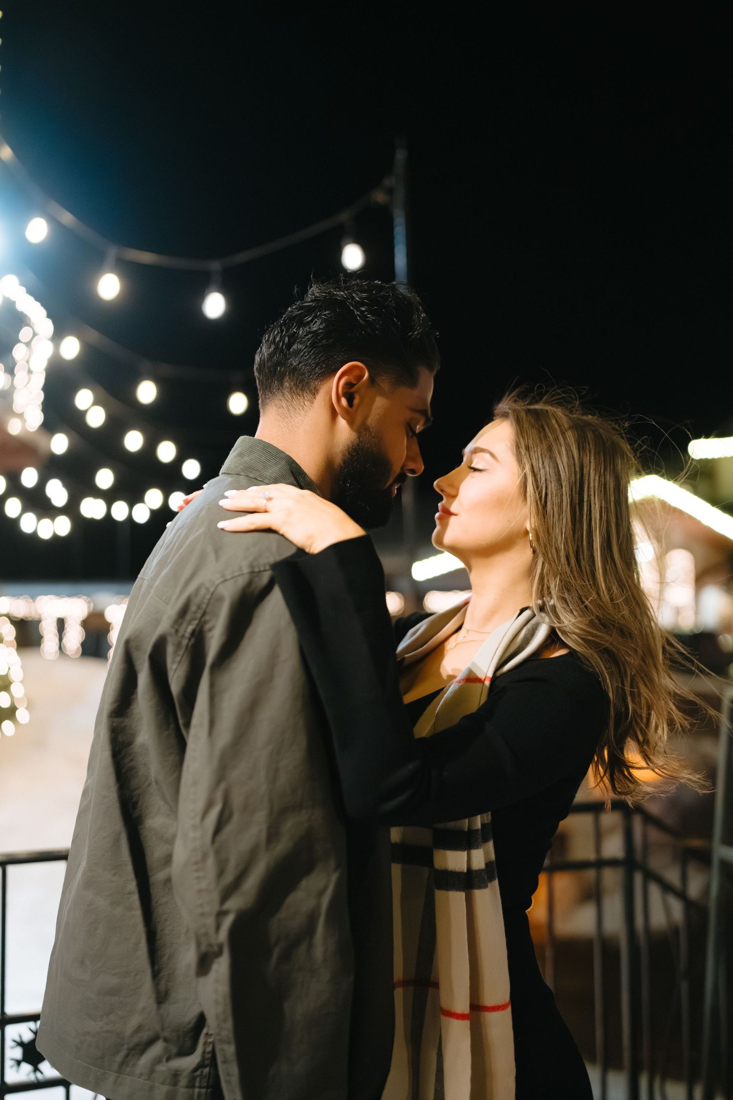 Romantic evening scene with string lights illuminating a couple's intimate moment.