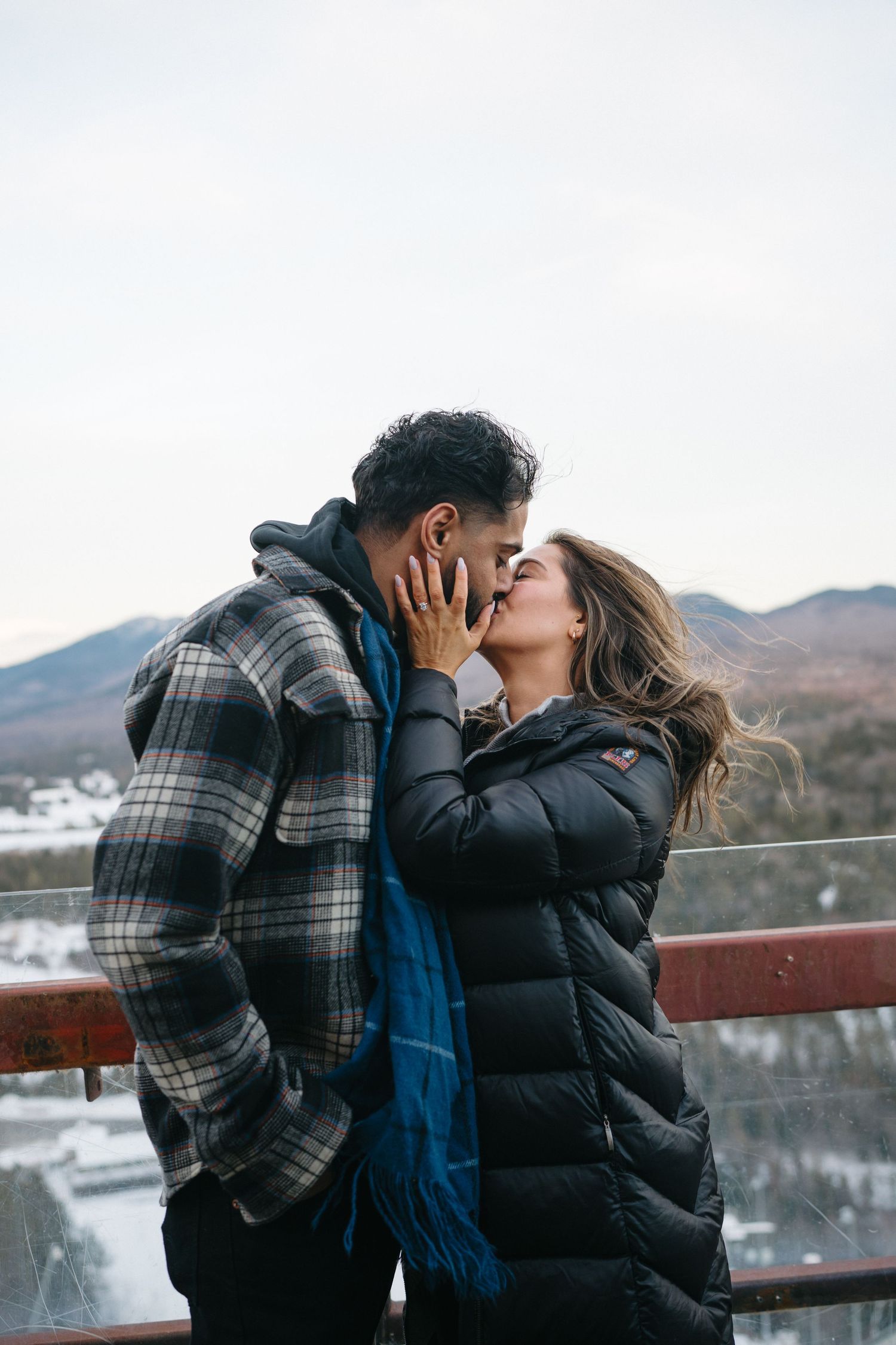 Romantic winter moment with a couple embracing against a snowy mountain backdrop.