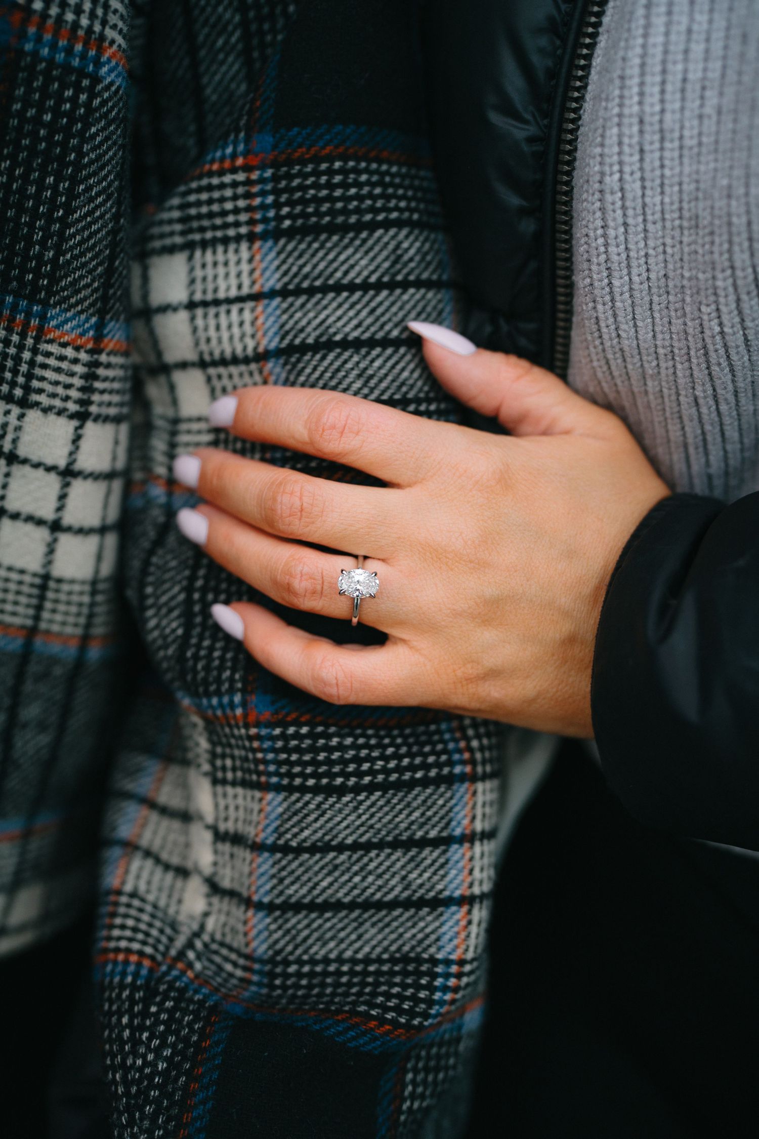 Close-up shots of an engagement ring on a hand against a plaid fabric background.