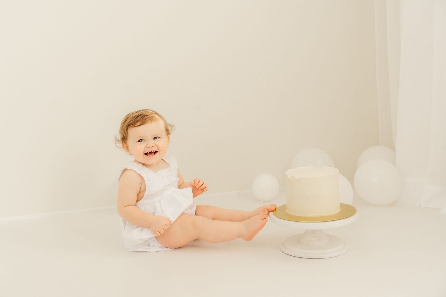 A cake smash photo collage featuring pink and white balloon decorations and a white smash cake with floral accents.