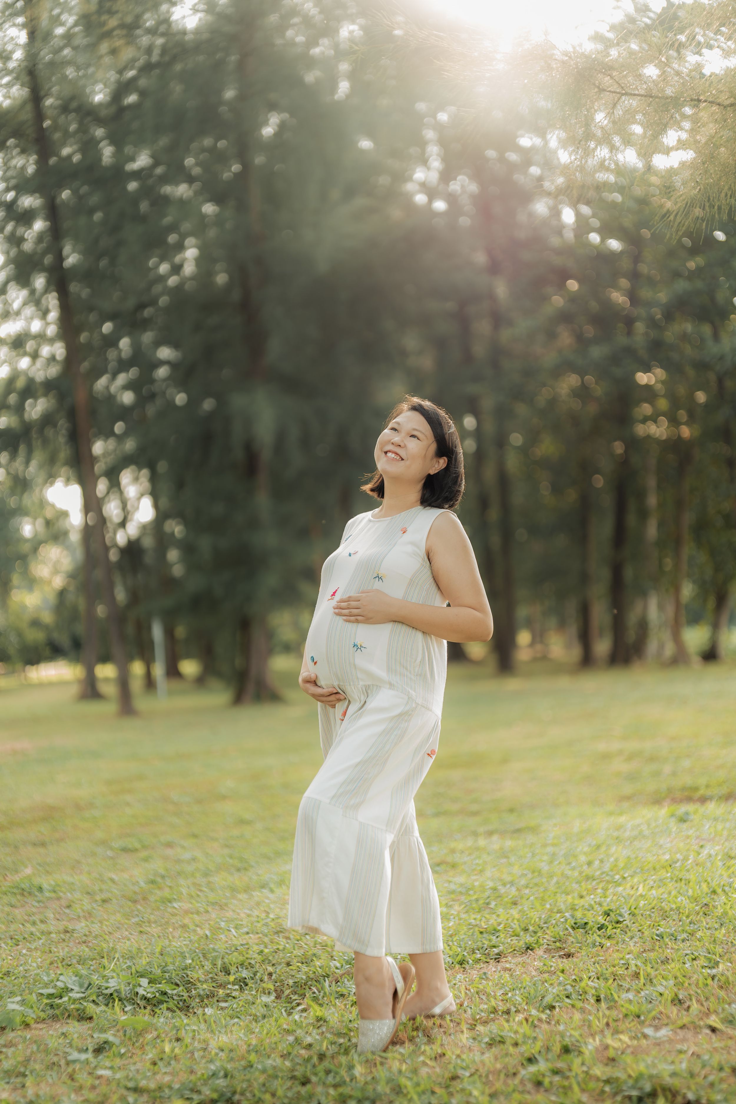 Person in white dress twirling joyfully in sunlit grassy field.