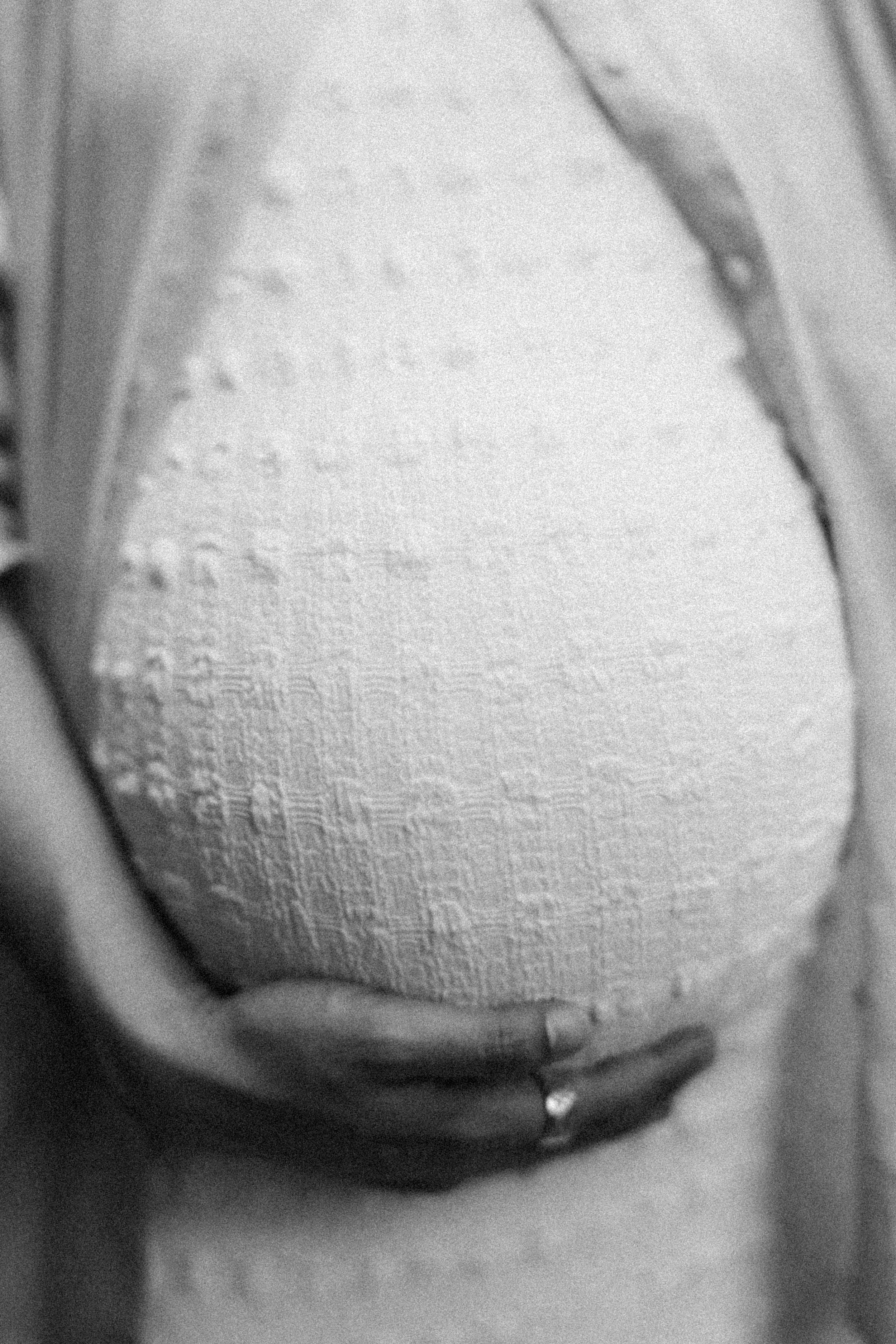 Black and white close-up of pregnant belly with textured fabric.