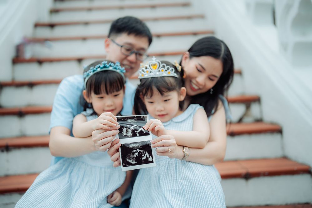 A family looking at an ultrasound photo together while sitting on wooden stairs.