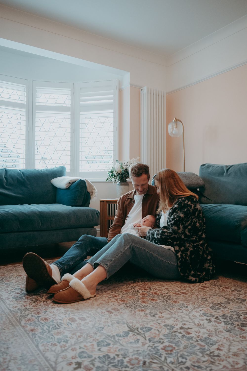 A sequence of people lounging and relaxing on a blue couch in a bright living room with patterned carpet.