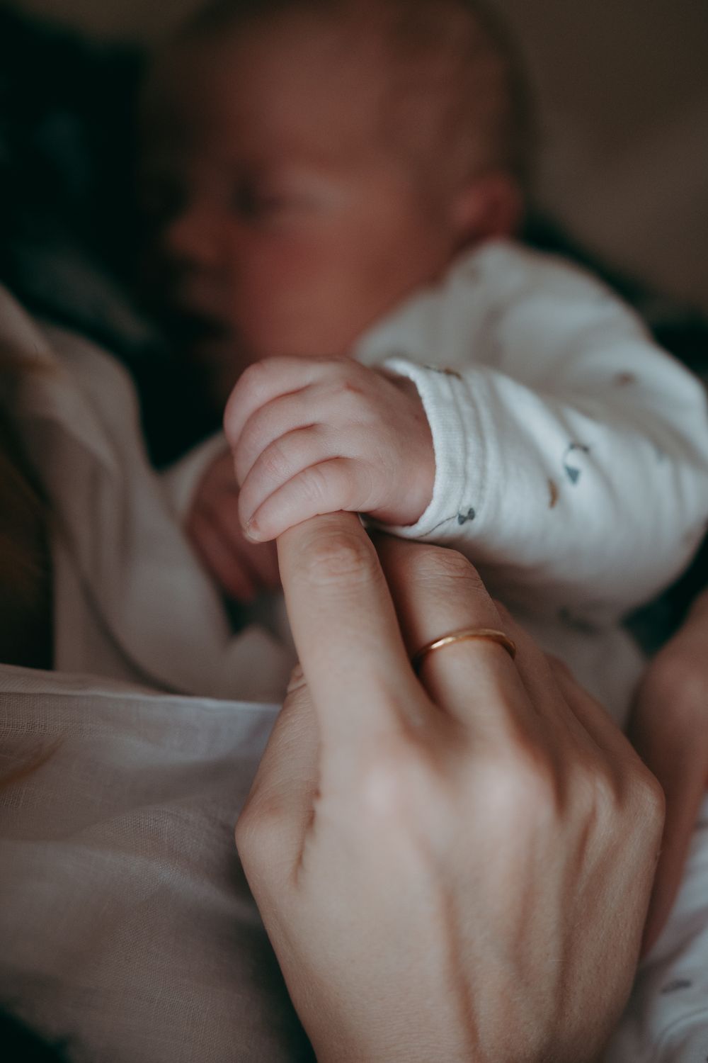 Close-up view of two hands with wedding rings touching gently in a tender moment.