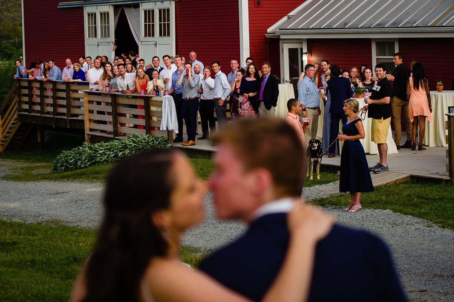 wedding couple sharing a kiss while their guests cheer, welcoming them to cocktail hour