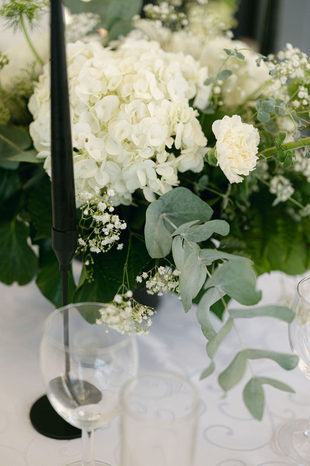 White floral centerpieces with eucalyptus leaves on reception tables.