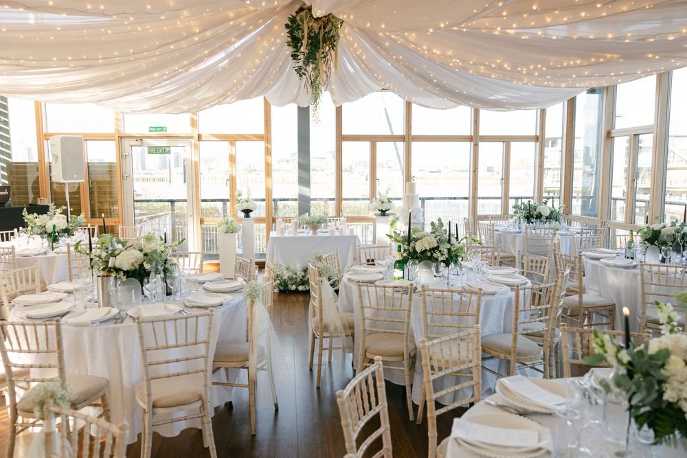 Elegant wedding reception hall with draped ceiling and chiavari chairs.