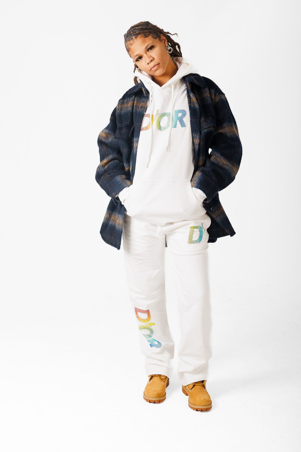 Stylish white sweatsuit with colorful alphabet letters paired with a denim jacket and brown boots against white backdrop.